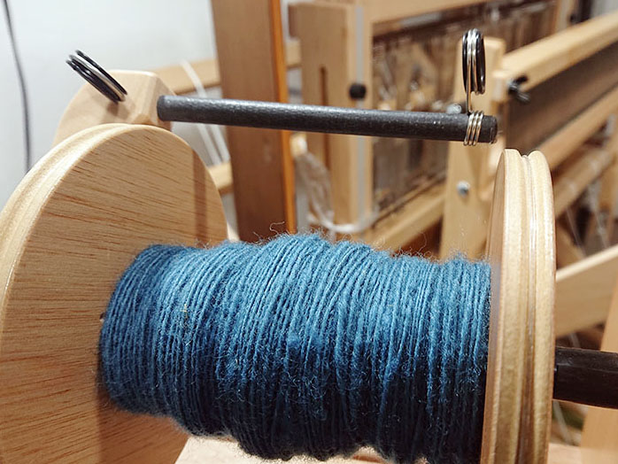 藍染めのウールを糸に紡ぐ。